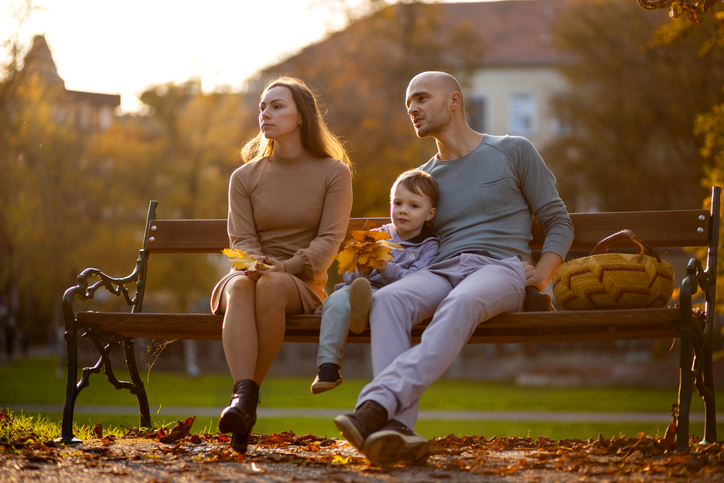 mother, father, and child sitting on a park bench - does texas have alimony in divorce